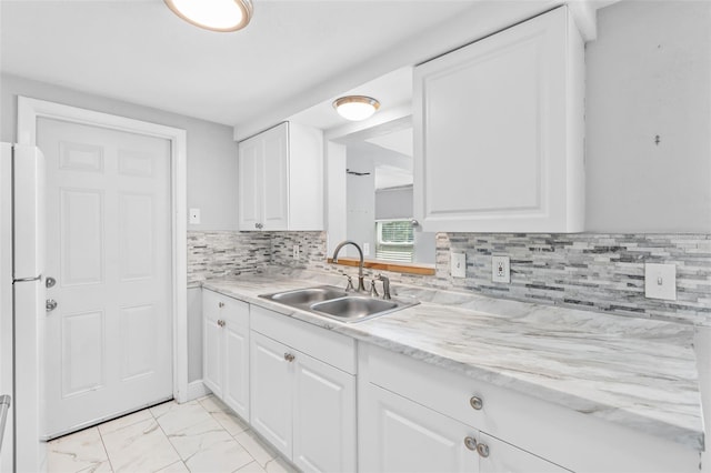 11326 Yellowwood Ln, Port Richey, FL 34668 - kitchen with freestanding refrigerator, white cabinets, tasteful backsplash, and light marble finish floors