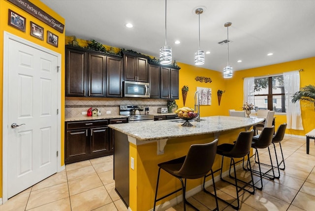 30300 Hackney Loop, Mount Dora, FL 32757 - kitchen featuring appliances with stainless steel finishes, tasteful backsplash, light tile patterned floors, light stone counters, and a breakfast bar area