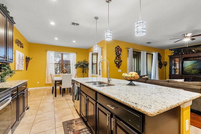 30300 Hackney Loop, Mount Dora, FL 32757 - kitchen featuring stainless steel appliances, hanging light fixtures, an island with sink, dark brown cabinetry, and light stone countertops