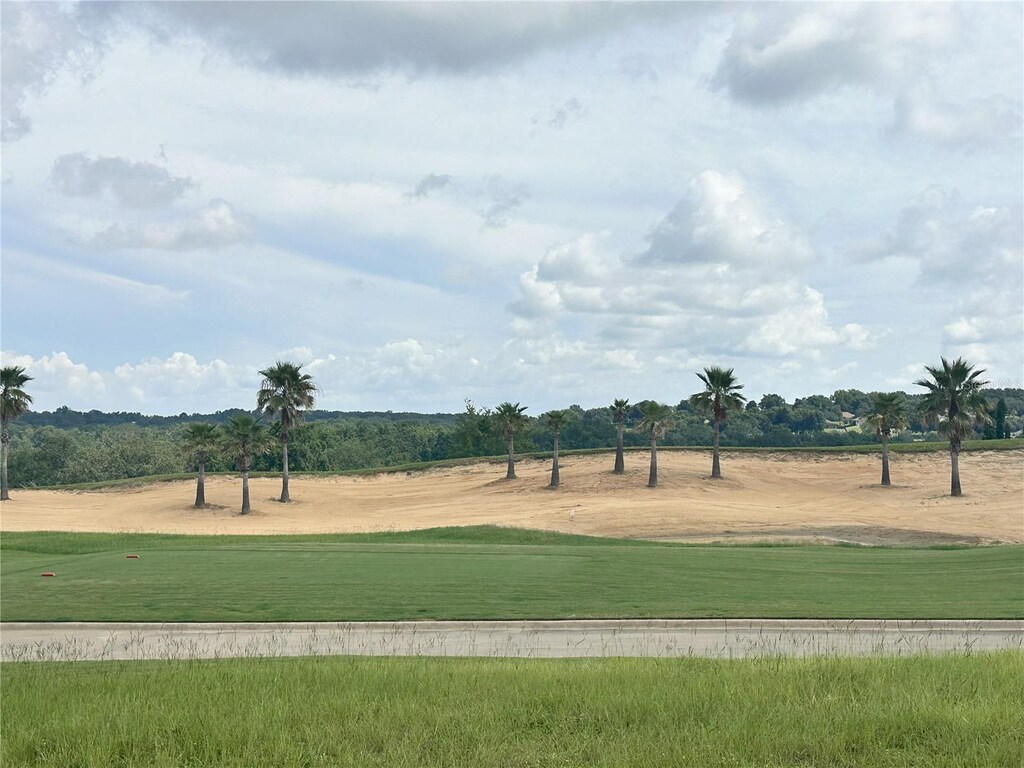 view of community featuring view of golf course and a lawn