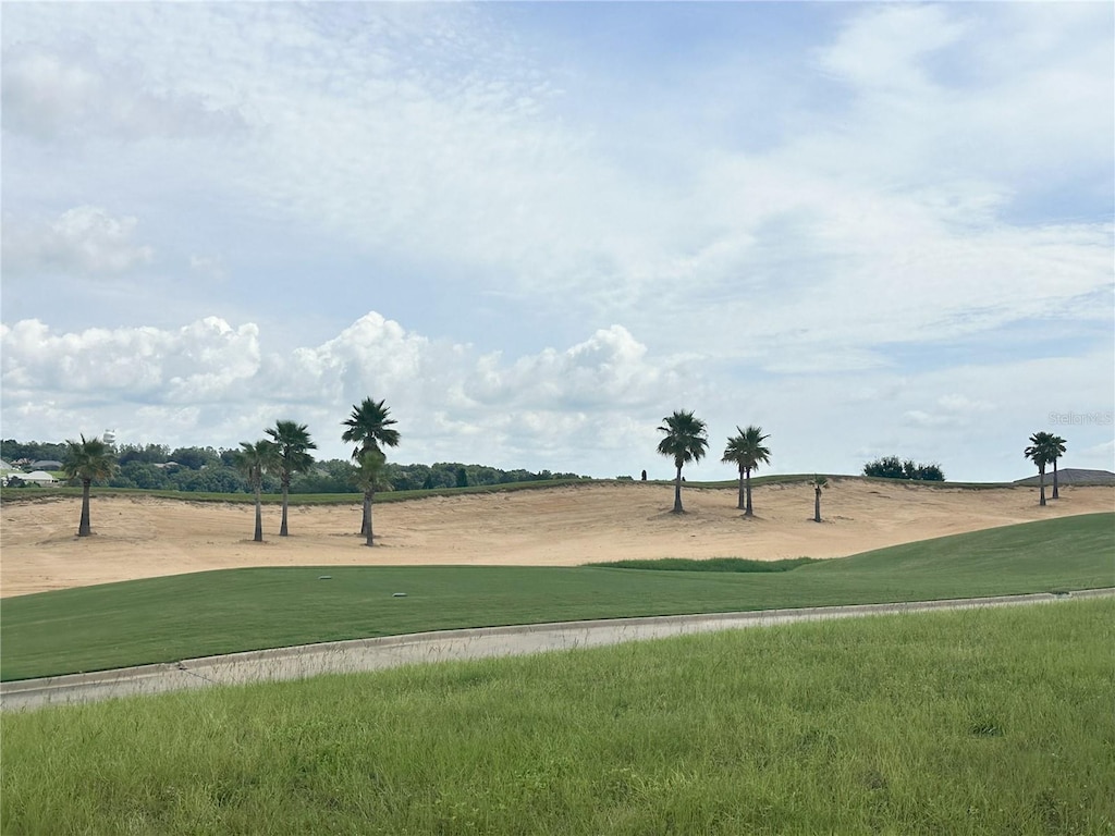 view of property's community featuring view of golf course and a yard