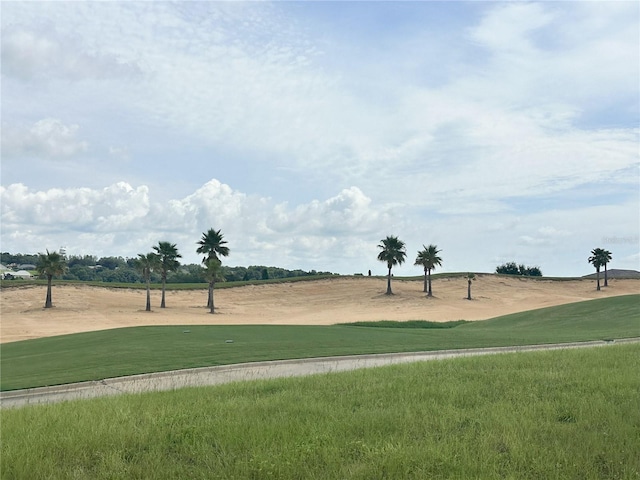 view of property's community featuring view of golf course and a yard