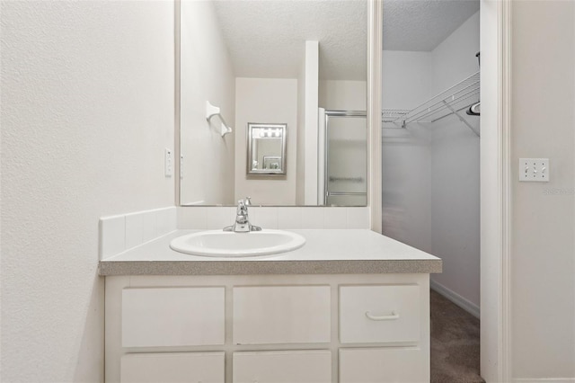324 Juniper Way, Tavares, FL 32778 - bathroom featuring vanity, a spacious closet, a textured ceiling, and a shower with door