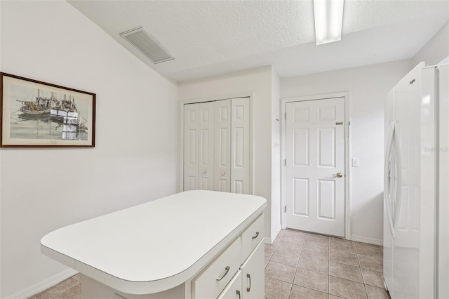 324 Juniper Way, Tavares, FL 32778 - bedroom featuring freestanding refrigerator, light tile patterned floors, a closet, and a textured ceiling