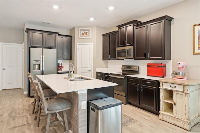 49 White Horse Way, Groveland, FL 34736 - kitchen featuring stainless steel appliances, light wood finished floors, a breakfast bar, dark brown cabinets, and light countertops
