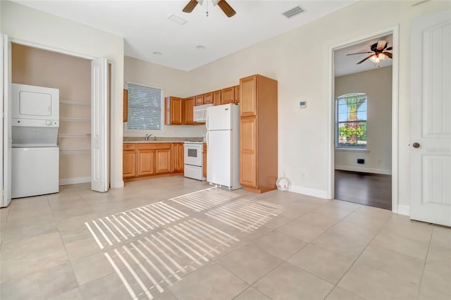 18139 Great Blue Heron Dr, Groveland, FL 34736 - kitchen featuring white appliances, ceiling fan, stacked washer and clothes dryer, light countertops, and light tile patterned floors