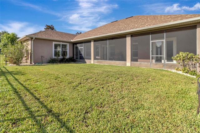 18139 Great Blue Heron Dr, Groveland, FL 34736 - rear view of house featuring a sunroom, a yard, stucco siding, and a shingled roof