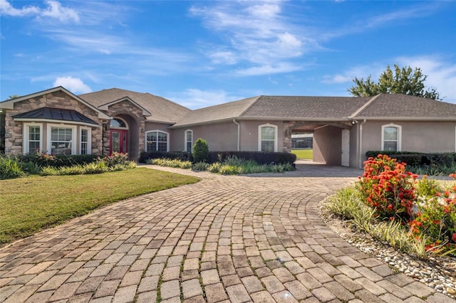 18139 Great Blue Heron Dr, Groveland, FL 34736 - ranch-style house featuring decorative driveway, stucco siding, a front lawn, and stone siding