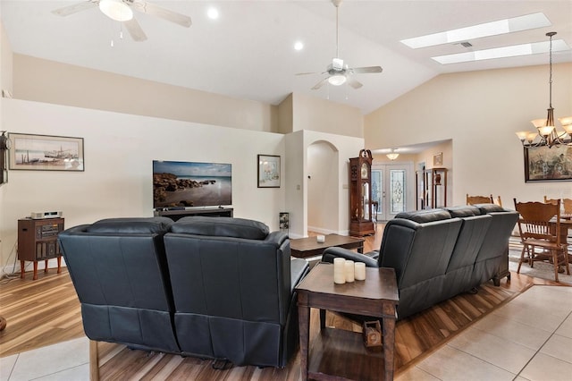 1412 Cove Pl, Tavares, FL 32778 - living room with a ceiling fan, light tile patterned flooring, a chandelier, a skylight, and high vaulted ceiling
