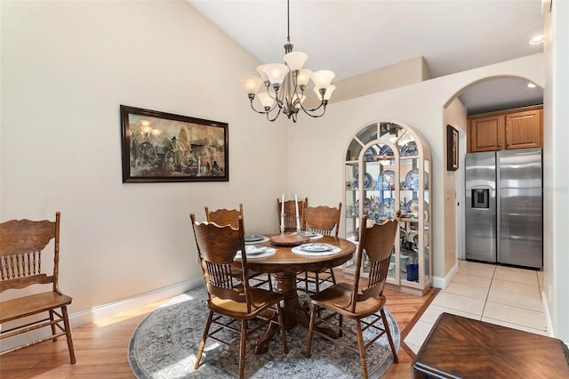 1412 Cove Pl, Tavares, FL 32778 - dining space with arched walkways, a chandelier, light wood-style flooring, and lofted ceiling