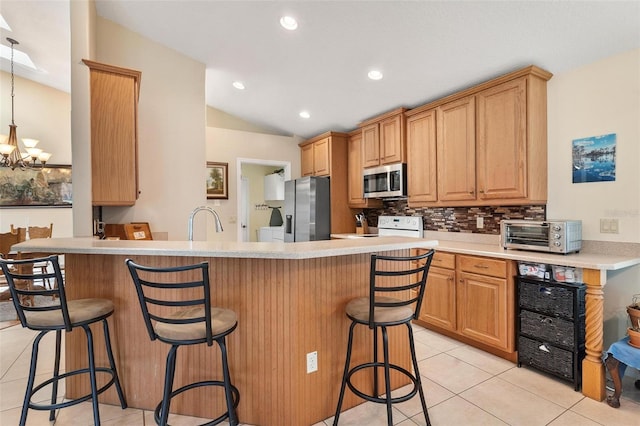 1412 Cove Pl, Tavares, FL 32778 - kitchen with stainless steel appliances, light tile patterned floors, a kitchen bar, lofted ceiling, and decorative backsplash