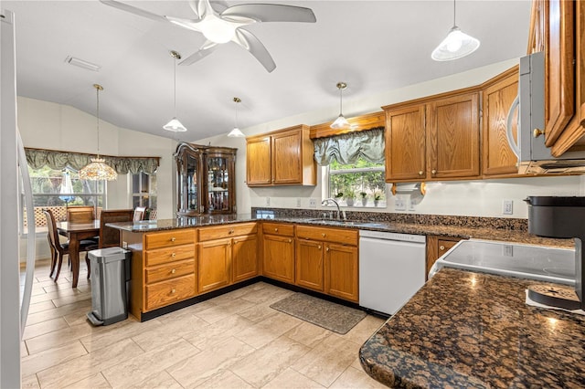 89 Palermo Pl, The Villages, FL 32159 - kitchen with white appliances, brown cabinets, a peninsula, vaulted ceiling, and decorative light fixtures