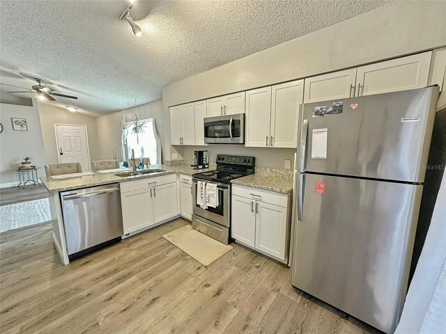 7047 Hickory Branch Cir, Orlando, FL 32818 - kitchen featuring appliances with stainless steel finishes, a peninsula, ceiling fan, white cabinets, and a textured ceiling