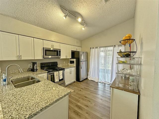 7047 Hickory Branch Cir, Orlando, FL 32818 - kitchen with stainless steel appliances, white cabinets, light stone counters, a textured ceiling, and light wood finished floors