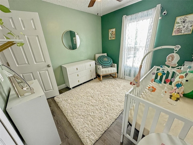 7047 Hickory Branch Cir, Orlando, FL 32818 - bedroom with a crib, wood finished floors, a textured ceiling, and ceiling fan