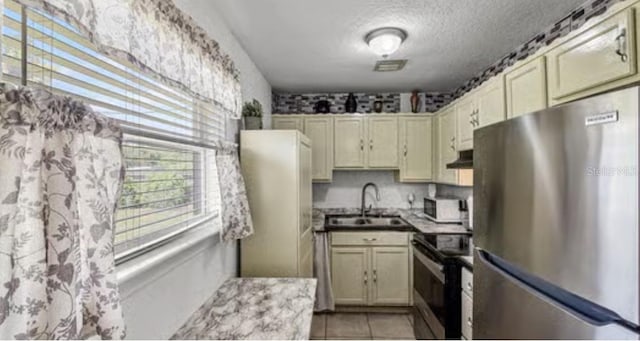 5912 Navajo Way, Orlando, FL 32807 - kitchen featuring stainless steel appliances, under cabinet range hood, a textured ceiling, and light tile patterned floors