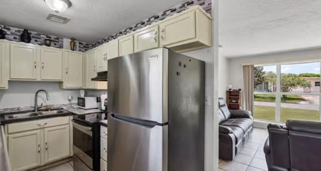 5912 Navajo Way, Orlando, FL 32807 - kitchen featuring appliances with stainless steel finishes, a textured ceiling, under cabinet range hood, light tile patterned flooring, and dark countertops