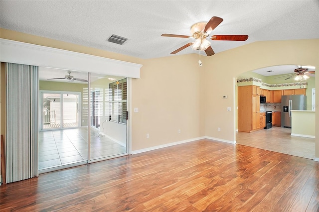 182 Palermo Pl, Lady Lake, FL 32159 - unfurnished room featuring a ceiling fan, light wood-style floors, a textured ceiling, vaulted ceiling, and arched walkways