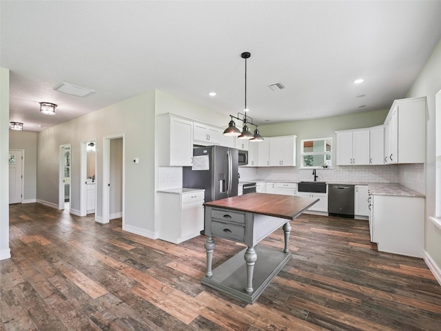 8567 Crk 635, Bushnell, FL 33513 - kitchen featuring appliances with stainless steel finishes, decorative backsplash, dark wood finished floors, white cabinets, and pendant lighting