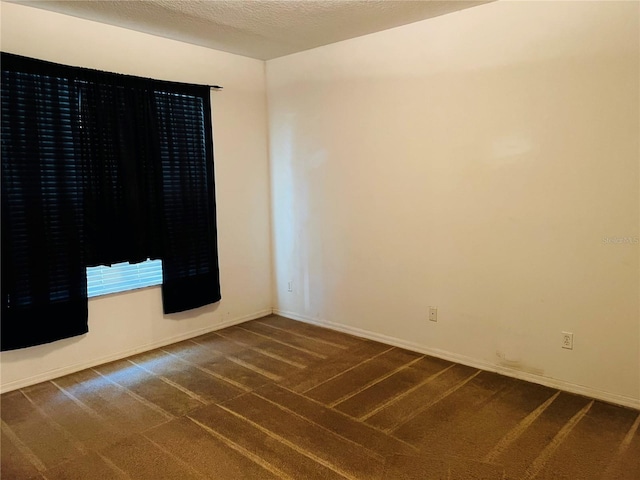 empty room featuring dark carpet and baseboards