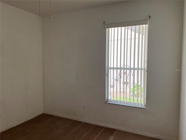 empty room with dark colored carpet and baseboards