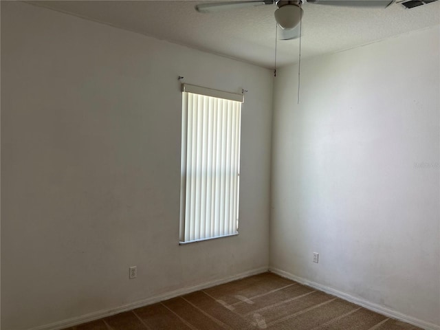 carpeted spare room featuring ceiling fan and baseboards
