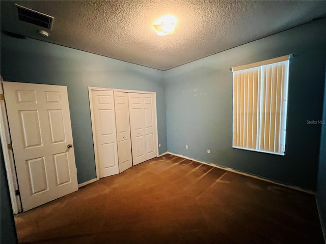 unfurnished bedroom with a textured ceiling, carpet, and a closet