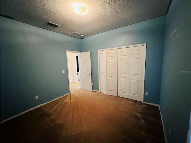 unfurnished bedroom with a textured ceiling, a closet, and carpet floors
