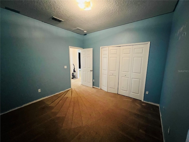 unfurnished bedroom with a textured ceiling, a closet, and carpet