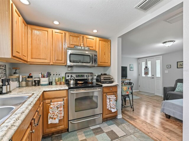 709 S Dixie Ave, Fruitland Park, FL 34731 - kitchen with stainless steel appliances, light countertops, recessed lighting, a textured ceiling, and light wood-style flooring