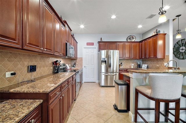 30230 Tokara Ter, Mount Dora, FL 32757 - kitchen featuring stainless steel appliances, a peninsula, light stone countertops, a kitchen bar, and recessed lighting