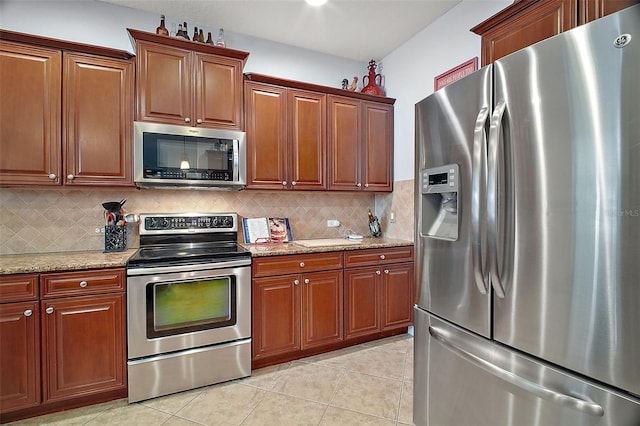 30230 Tokara Ter, Mount Dora, FL 32757 - kitchen with appliances with stainless steel finishes, light tile patterned floors, decorative backsplash, light stone counters, and brown cabinets