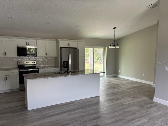 6805 N Sandborn Loop, Citrus Springs, FL 34433 - kitchen with appliances with stainless steel finishes, a chandelier, a textured ceiling, decorative backsplash, and an island with sink