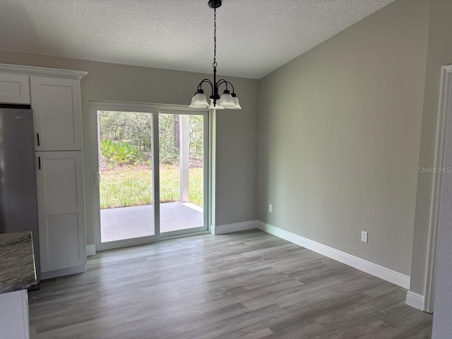 6805 N Sandborn Loop, Citrus Springs, FL 34433 - unfurnished dining area featuring a chandelier, light wood-type flooring, and a textured ceiling