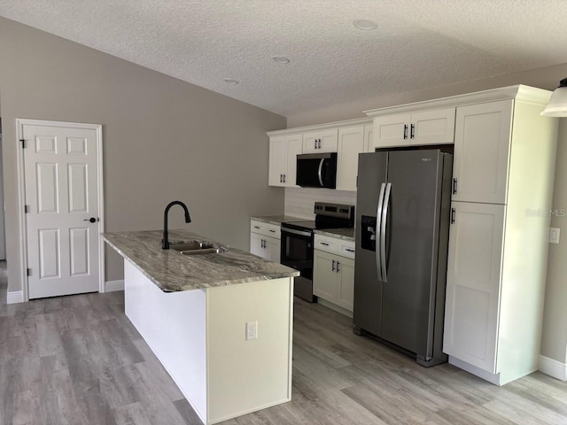 6805 N Sandborn Loop, Citrus Springs, FL 34433 - kitchen with stainless steel appliances, white cabinets, light wood-style flooring, a kitchen island with sink, and a textured ceiling