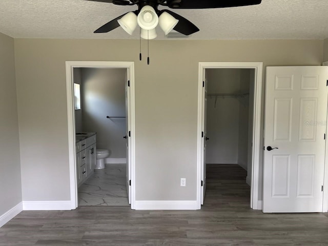 6805 N Sandborn Loop, Citrus Springs, FL 34433 - unfurnished bedroom with a spacious closet, a closet, a textured ceiling, ensuite bathroom, and wood finished floors
