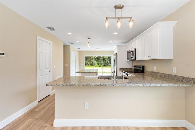 577 E Anderson Ave, Bushnell, FL 33513 - kitchen featuring appliances with stainless steel finishes, a peninsula, light wood finished floors, white cabinets, and light stone counters