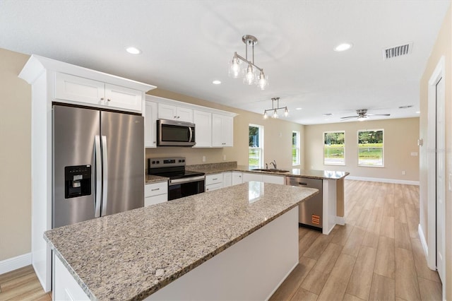 577 E Anderson Ave, Bushnell, FL 33513 - kitchen with appliances with stainless steel finishes, a peninsula, a kitchen island, light wood-type flooring, and white cabinets