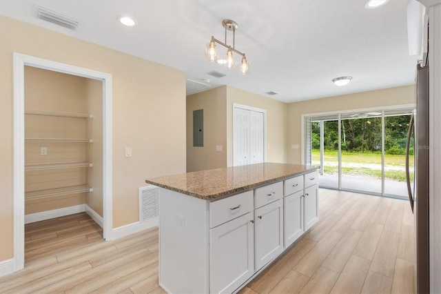 577 E Anderson Ave, Bushnell, FL 33513 - kitchen with light wood-style floors, electric panel, white cabinetry, light stone counters, and a kitchen island