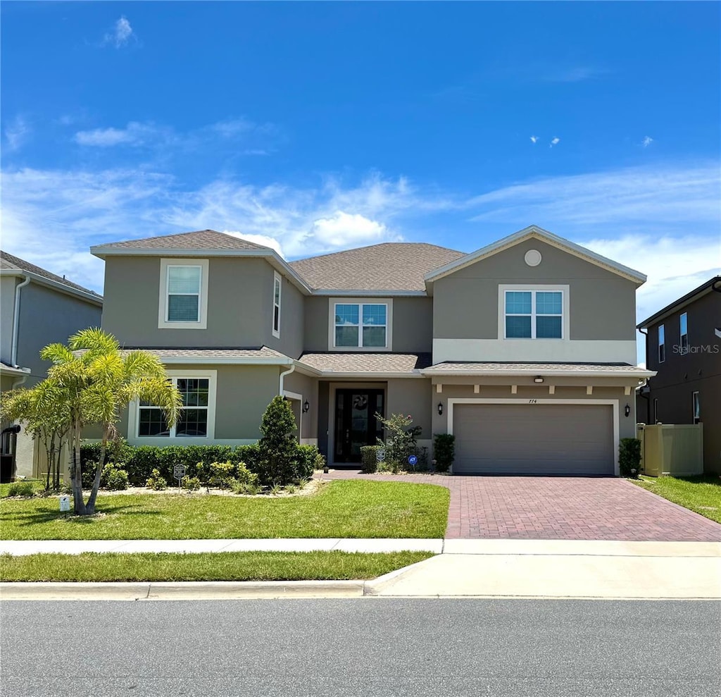 7740 Marsala St, Clermont, FL 34714 - traditional-style home with stucco siding, decorative driveway, an attached garage, and a front lawn