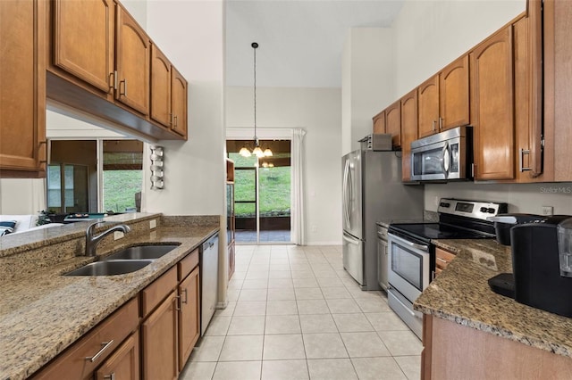 1532 Nightfall Dr, Clermont, FL 34711 - kitchen with appliances with stainless steel finishes, brown cabinets, stone countertops, and a chandelier