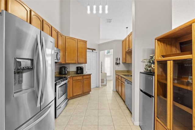 1532 Nightfall Dr, Clermont, FL 34711 - kitchen featuring stainless steel appliances, light tile patterned floors, brown cabinets, a high ceiling, and pendant lighting