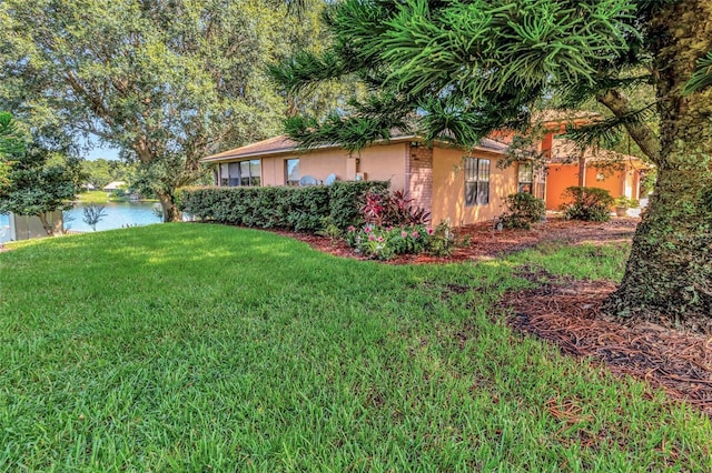 9835 Lakeshore Dr, Clermont, FL 34711 - view of home's exterior with a lawn, a water view, and stucco siding