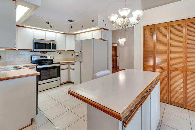 9835 Lakeshore Dr, Clermont, FL 34711 - kitchen featuring appliances with stainless steel finishes, a chandelier, white cabinets, light tile patterned flooring, and light countertops