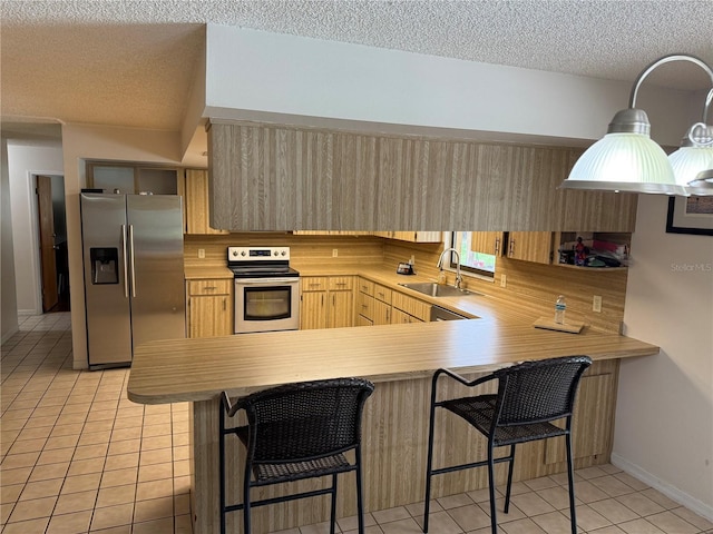 2747 County Road 615, Bushnell, FL 33513 - kitchen with stainless steel appliances, a textured ceiling, light brown cabinetry, light countertops, and a peninsula