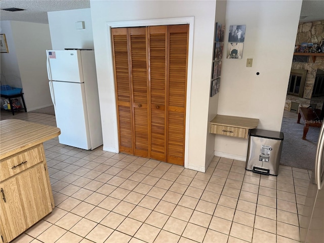 2747 County Road 615, Bushnell, FL 33513 - kitchen featuring freestanding refrigerator, light tile patterned floors, a stone fireplace, and light brown cabinets