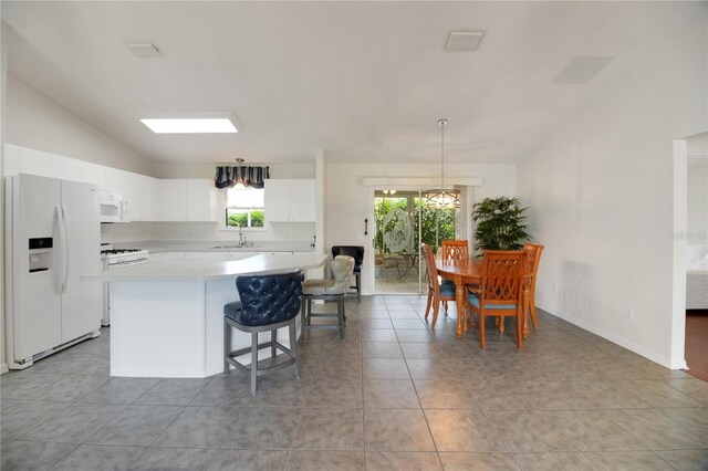 17707 SE 92nd Grantham Ter, The Villages, FL 32162 - kitchen featuring white appliances, lofted ceiling, light countertops, a center island, and white cabinetry