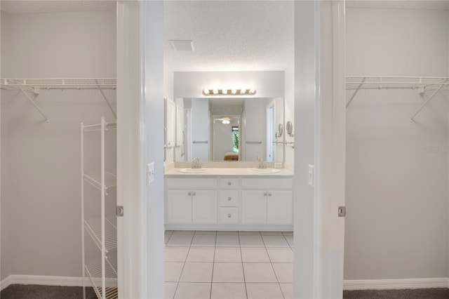 17707 SE 92nd Grantham Ter, The Villages, FL 32162 - bathroom with double vanity, a textured ceiling, tile patterned flooring, and a walk in closet
