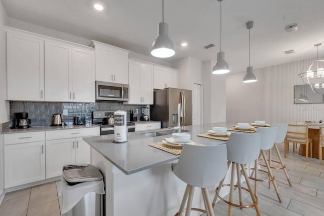 8971 Cabot Cliffs Dr, Davenport, FL 33896 - kitchen with stainless steel appliances, white cabinets, a kitchen breakfast bar, backsplash, and an island with sink