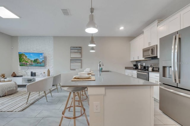 8971 Cabot Cliffs Dr, Davenport, FL 33896 - kitchen with appliances with stainless steel finishes, a center island with sink, white cabinetry, light tile patterned flooring, and recessed lighting